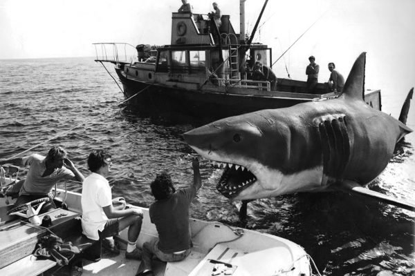 A crew member inspecting the animatronic shark used in Steven Spielberg’s Jaws (1975), revealing the mechanical structure beneath the realistic exterior